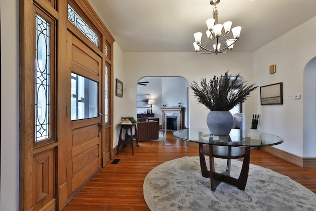 398 W 5th Ave, Columbus, OH 43201 - foyer entrance with arched walkways, dark wood-style floors, a fireplace, and a chandelier