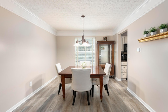 6258 Tetlin Field Dr, New Albany, OH 43054 - dining space with a chandelier, a textured ceiling, light wood finished floors, and crown molding