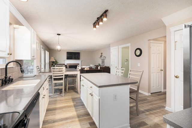 6258 Tetlin Field Dr, New Albany, OH 43054 - kitchen featuring stainless steel dishwasher, a kitchen bar, light wood-type flooring, white cabinetry, and a fireplace