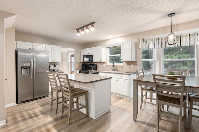 6258 Tetlin Field Dr, New Albany, OH 43054 - kitchen with black appliances, light wood-style floors, tasteful backsplash, white cabinetry, and a textured ceiling