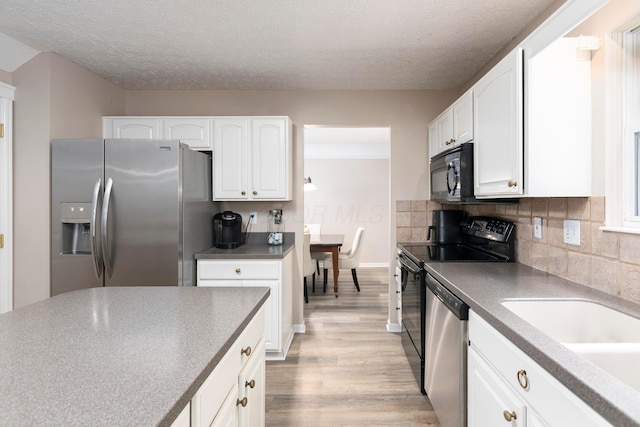 6258 Tetlin Field Dr, New Albany, OH 43054 - kitchen featuring stainless steel appliances, light wood-type flooring, white cabinetry, tasteful backsplash, and dark countertops