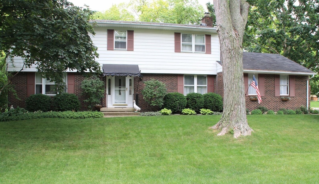 4570 Cassill St, Columbus, OH 43220 - view of front of home featuring brick siding, a chimney, and a front lawn