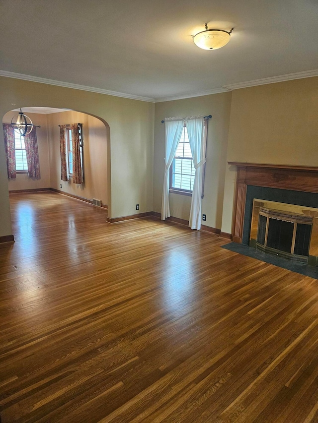 521 E Allen St, Lancaster, OH 43130 - unfurnished living room featuring arched walkways, wood finished floors, healthy amount of natural light, a tiled fireplace, and crown molding