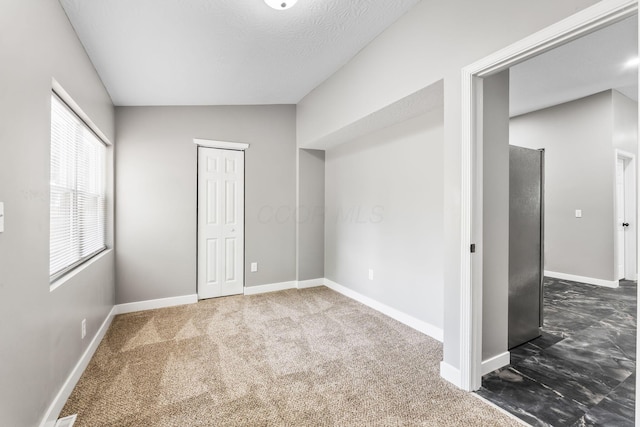 1612 Cole St, Columbus, OH 43205 - unfurnished bedroom featuring dark carpet, freestanding refrigerator, a closet, and vaulted ceiling