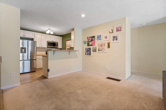 4109 Blendon Way Dr Unit 99E, Columbus, OH 43230 - kitchen featuring appliances with stainless steel finishes, light carpet, a textured ceiling, white cabinetry, and open floor plan