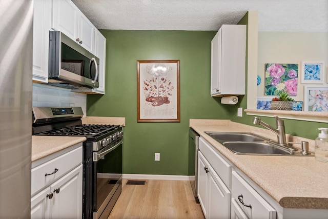 4109 Blendon Way Dr Unit 99E, Columbus, OH 43230 - kitchen with appliances with stainless steel finishes, white cabinets, light wood-type flooring, light countertops, and a textured ceiling