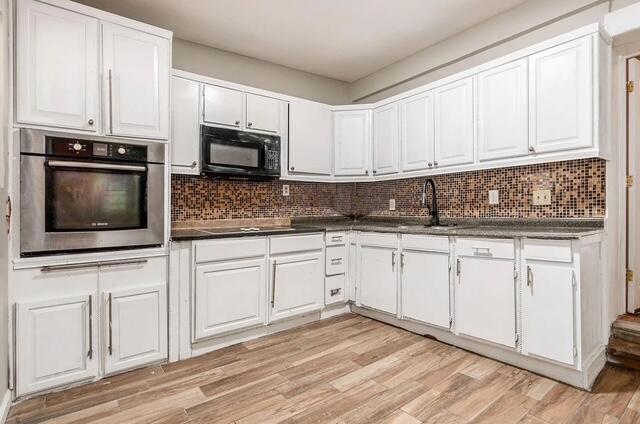 1364 E Fulton St, Columbus, OH 43205 - kitchen with black appliances, dark countertops, white cabinetry, and tasteful backsplash