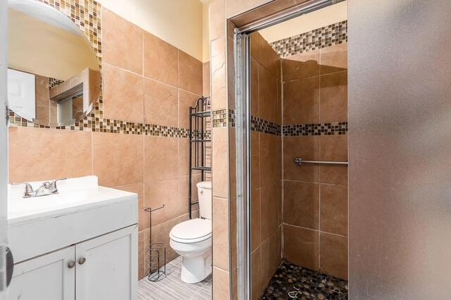 1364 E Fulton St, Columbus, OH 43205 - bathroom featuring tile walls, a shower stall, and vanity