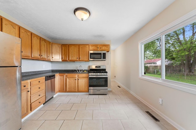 893 Aladdin Ct, Columbus, OH 43207 - kitchen with stainless steel appliances, dark countertops, decorative backsplash, and light tile patterned flooring