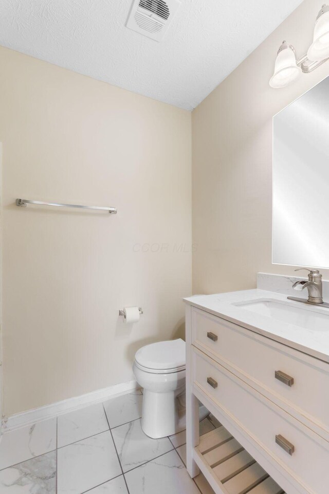 893 Aladdin Ct, Columbus, OH 43207 - bathroom featuring marble look tile flooring, vanity, and a textured ceiling