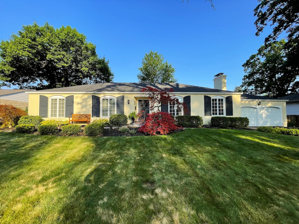 3169 Halesworth Rd, Columbus, OH 43221 - ranch-style home with an attached garage, a chimney, a front lawn, and stucco siding