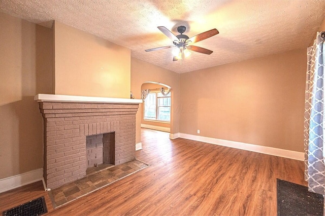 330 S Harris Ave, Columbus, OH 43204 - unfurnished living room featuring a textured ceiling, a brick fireplace, a ceiling fan, and wood finished floors