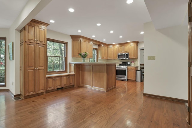 1100 Riva Ridge Blvd, Columbus, OH 43230 - kitchen with appliances with stainless steel finishes, a peninsula, wood finished floors, recessed lighting, and brown cabinetry