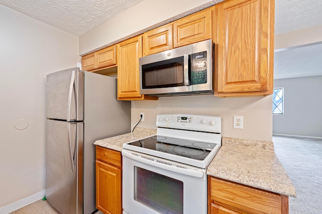 3033 Highcliff Ct, Columbus, OH 43231 - kitchen featuring appliances with stainless steel finishes, a textured ceiling, light carpet, and light stone counters