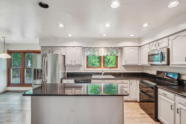 4867 Sarasota Ct, Hilliard, OH 43026 - kitchen featuring appliances with stainless steel finishes, a kitchen island, light wood-type flooring, dark stone countertops, and white cabinetry
