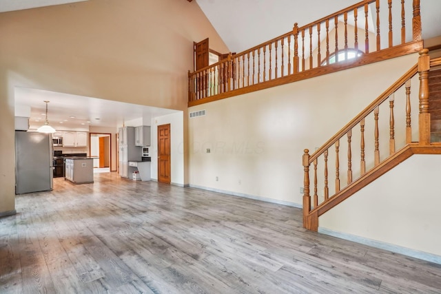 4867 Sarasota Ct, Hilliard, OH 43026 - unfurnished living room with light wood-style flooring, high vaulted ceiling, and stairway