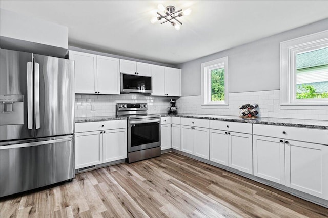 114 N 7th St, Newark, OH 43055 - kitchen with appliances with stainless steel finishes, light wood-type flooring, white cabinetry, decorative backsplash, and dark stone countertops