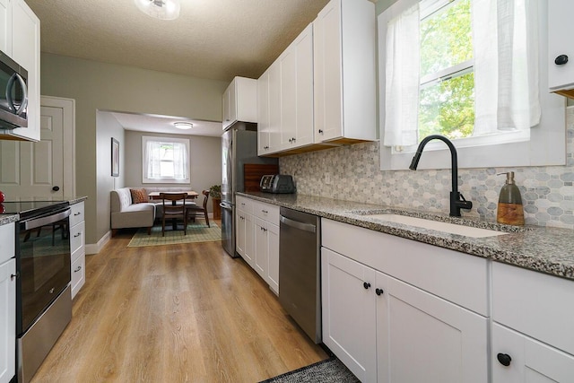 2686 Wicklow Rd, Columbus, OH 43204 - kitchen with stainless steel appliances, light wood-type flooring, backsplash, white cabinets, and a textured ceiling