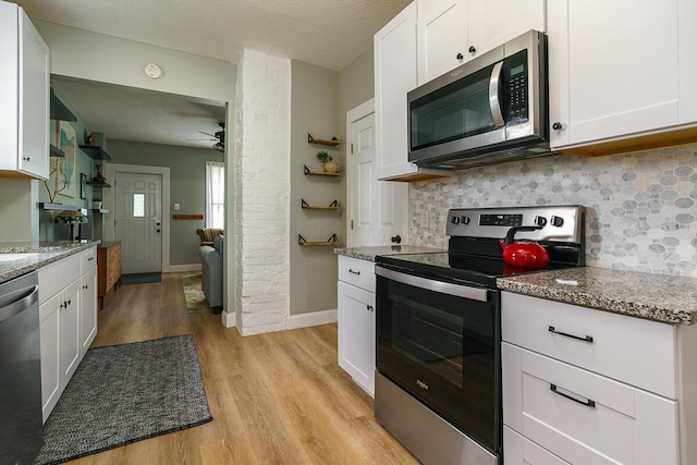 2686 Wicklow Rd, Columbus, OH 43204 - kitchen with stainless steel appliances, light wood finished floors, tasteful backsplash, white cabinets, and a textured ceiling