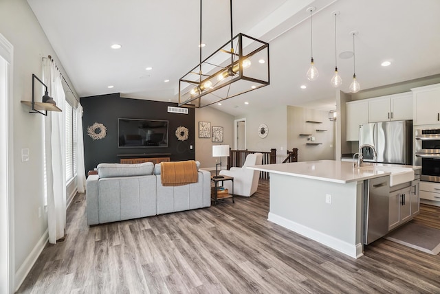25500 Storms Rd, West Mansfield, OH 43358 - kitchen with stainless steel appliances, light countertops, vaulted ceiling, wood finished floors, and a kitchen island with sink