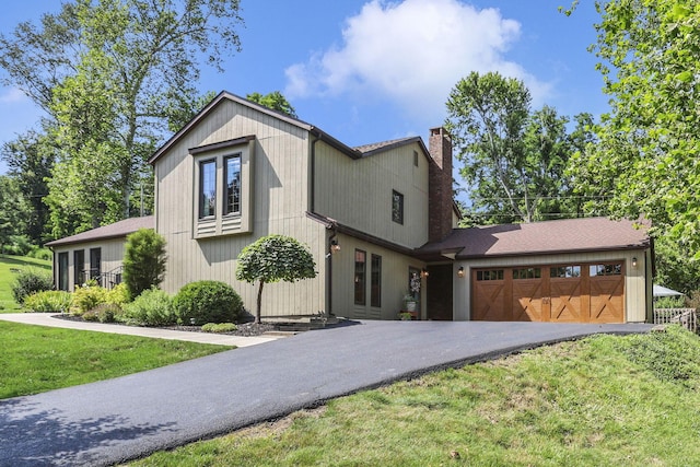 680 Rainbow Dr NW, Lancaster, OH 43130 - view of front of home with an attached garage, asphalt driveway, a chimney, and a front lawn