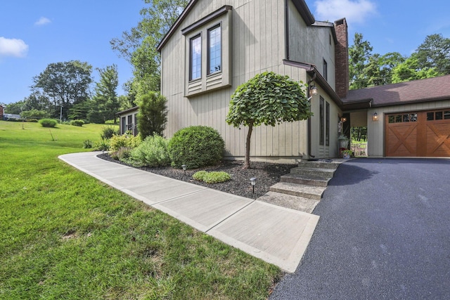 680 Rainbow Dr NW, Lancaster, OH 43130 - view of side of property featuring a garage, a yard, a chimney, and asphalt driveway