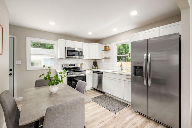 3432 Walmar Dr, Columbus, OH 43224 - kitchen featuring stainless steel appliances, white cabinets, open shelves, light wood-type flooring, and decorative backsplash