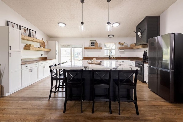 9710 Butcher Rd, Mount Vernon, OH 43050 - kitchen featuring open shelves, freestanding refrigerator, a textured ceiling, range with electric stovetop, and a kitchen bar