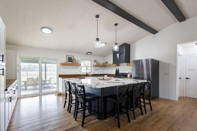 9710 Butcher Rd, Mount Vernon, OH 43050 - kitchen featuring open shelves, freestanding refrigerator, a textured ceiling, light wood-style floors, and a kitchen breakfast bar