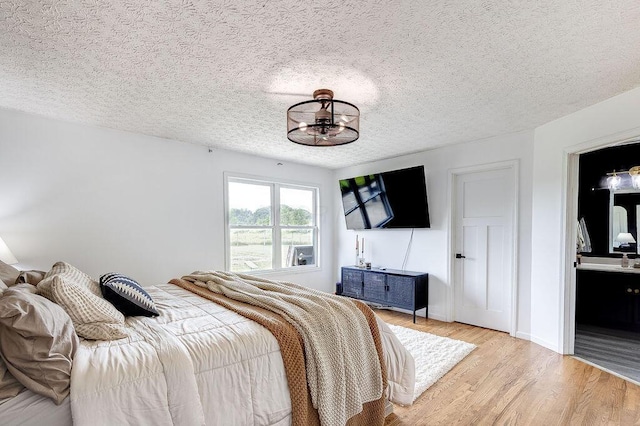 9710 Butcher Rd, Mount Vernon, OH 43050 - bedroom with light wood-style flooring, a chandelier, a textured ceiling, and ensuite bath