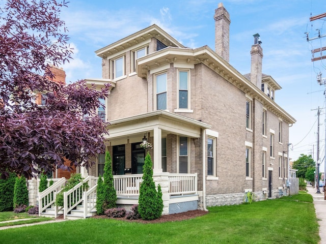 119 Miami Ave Unit 119, Columbus, OH 43203 - view of front of home featuring covered porch, brick siding, a chimney, and a front yard