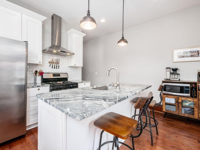 119 Miami Ave Unit 119, Columbus, OH 43203 - kitchen featuring appliances with stainless steel finishes, wall chimney range hood, dark wood-type flooring, decorative backsplash, and white cabinets