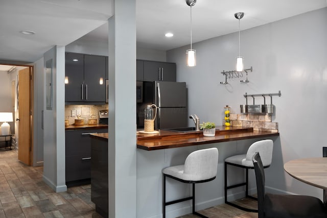 1481 Cliff Ct Unit 58-A, Columbus, OH 43204 - kitchen with freestanding refrigerator, decorative backsplash, a breakfast bar, butcher block counters, and dark wood finished floors