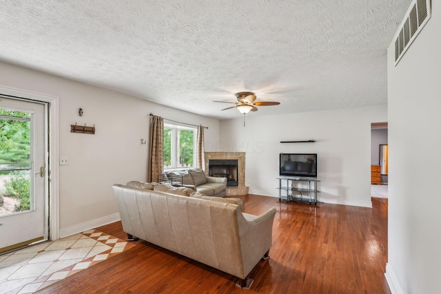9900 Waterloo Eastern Rd, Canal Winchester, OH 43110 - living room with hardwood / wood-style floors, a ceiling fan, a fireplace with raised hearth, and a textured ceiling