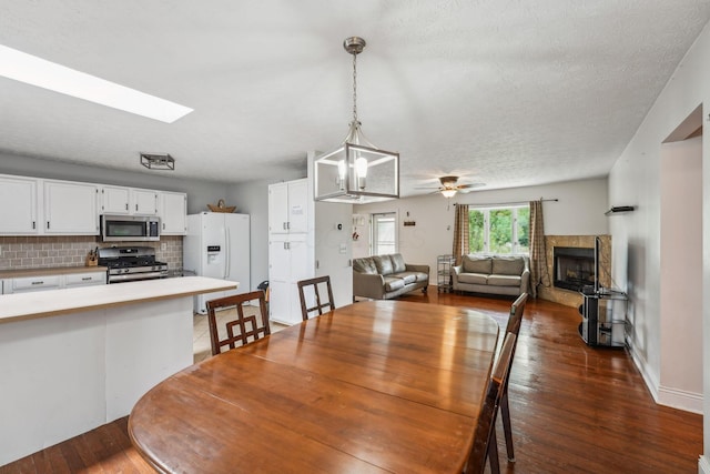 9900 Waterloo Eastern Rd, Canal Winchester, OH 43110 - dining room with dark wood-style flooring, a fireplace, ceiling fan, a chandelier, and a skylight