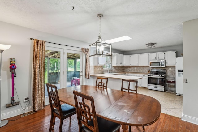 9900 Waterloo Eastern Rd, Canal Winchester, OH 43110 - dining space with light wood-style flooring, a chandelier, a skylight, and a textured ceiling