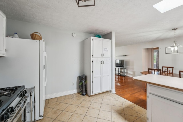 9900 Waterloo Eastern Rd, Canal Winchester, OH 43110 - kitchen with white cabinetry, light tile patterned floors, stainless steel range with gas stovetop, pendant lighting, and a skylight