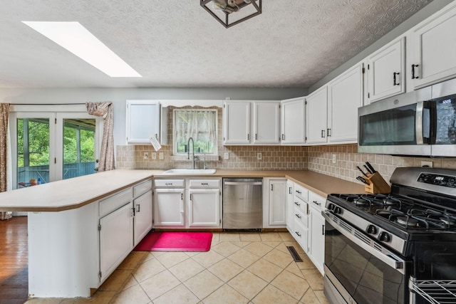 9900 Waterloo Eastern Rd, Canal Winchester, OH 43110 - kitchen with appliances with stainless steel finishes, a peninsula, a skylight, light countertops, and tasteful backsplash