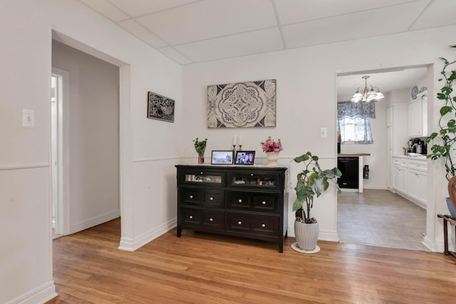 220 Robinwood Ave, Columbus, OH 43213 - hallway with a chandelier, light wood-style flooring, and a paneled ceiling