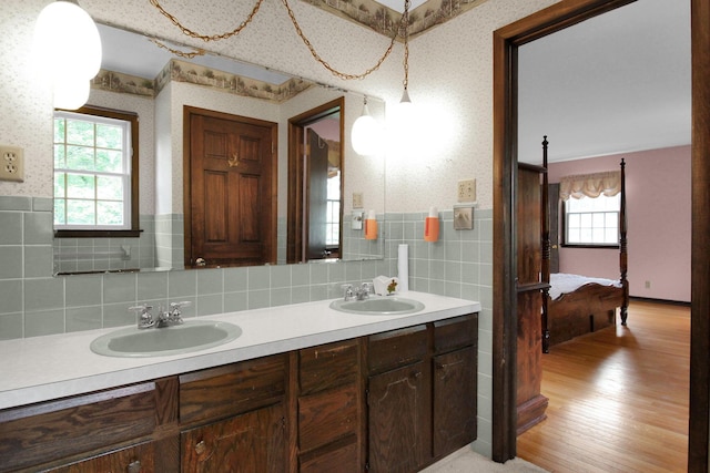 2399 Arabelle Dr NE, Lancaster, OH 43130 - full bath with double vanity, wood finished floors, wallpapered walls, decorative backsplash, and ensuite bathroom