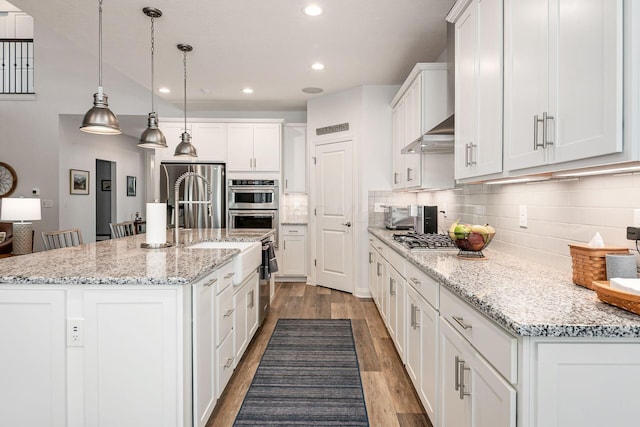 5540 Eva Loop S, Dublin, OH 43016 - kitchen featuring white cabinets, wood finished floors, appliances with stainless steel finishes, decorative backsplash, and recessed lighting
