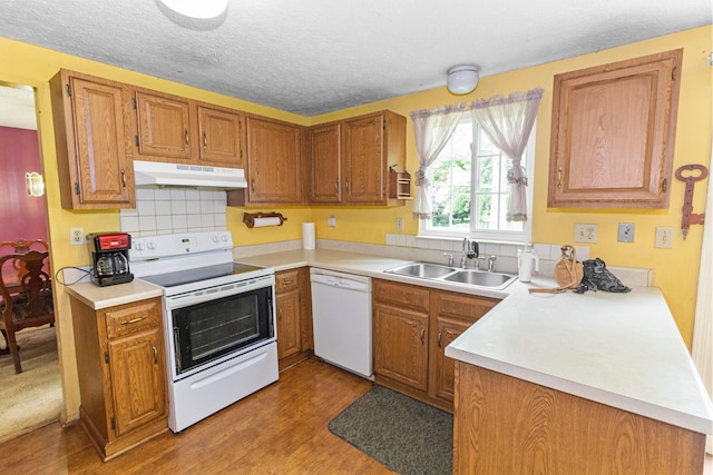 5500 Saddlebrook Dr, Columbus, OH 43221 - kitchen with white appliances, under cabinet range hood, wood finished floors, brown cabinetry, and light countertops