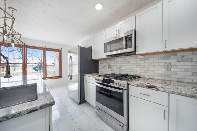 5583 Durrett Rd, Orient, OH 43146 - kitchen with appliances with stainless steel finishes, white cabinetry, tasteful backsplash, light stone countertops, and a textured ceiling