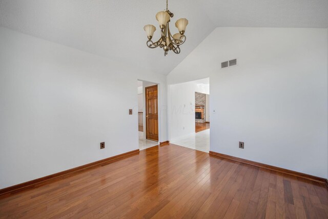 5583 Durrett Rd, Orient, OH 43146 - spare room featuring a chandelier, wood finished floors, high vaulted ceiling, and a fireplace with raised hearth