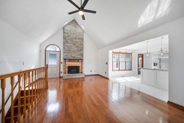 5583 Durrett Rd, Orient, OH 43146 - unfurnished living room with a ceiling fan, light wood-style floors, high vaulted ceiling, and a brick fireplace
