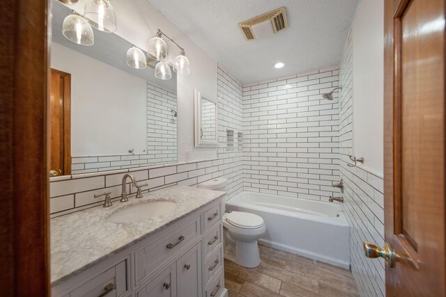 5583 Durrett Rd, Orient, OH 43146 - full bath with vanity, tile walls, tub / shower combination, a textured ceiling, and wood finished floors