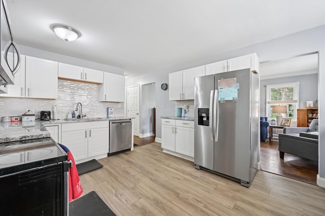 2931 Templeton Rd, Columbus, OH 43209 - kitchen featuring appliances with stainless steel finishes, decorative backsplash, light wood-type flooring, light stone countertops, and white cabinetry