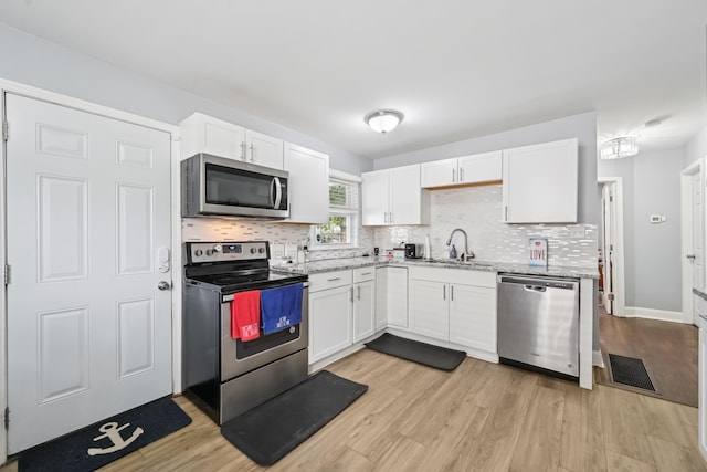 2931 Templeton Rd, Columbus, OH 43209 - kitchen with appliances with stainless steel finishes, white cabinets, light wood-style floors, and backsplash