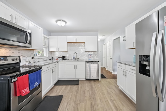 2931 Templeton Rd, Columbus, OH 43209 - kitchen with stainless steel appliances, light wood-style flooring, decorative backsplash, and white cabinets