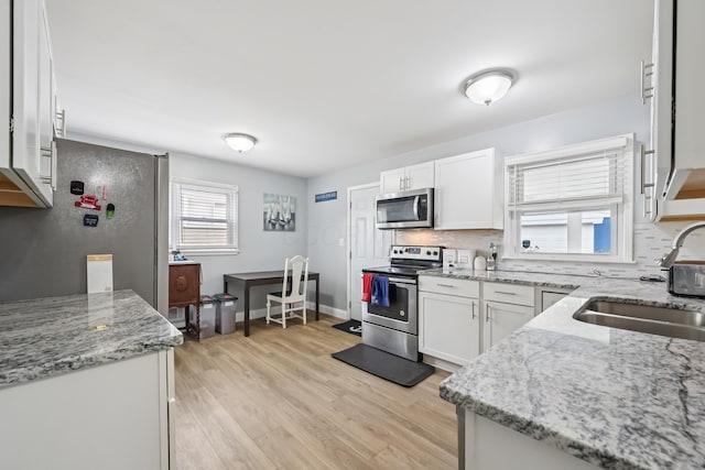 2931 Templeton Rd, Columbus, OH 43209 - kitchen with stainless steel appliances, decorative backsplash, light wood-style floors, white cabinetry, and light stone counters